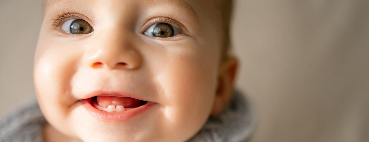 Ein Kind mit einem grauen Schal, das leicht zur Seite schaut. Der Hintergrund ist unscharf.